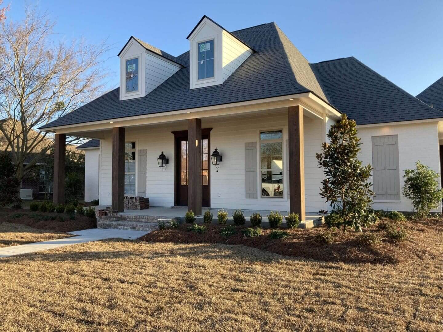 White house with porch and gabled roof.