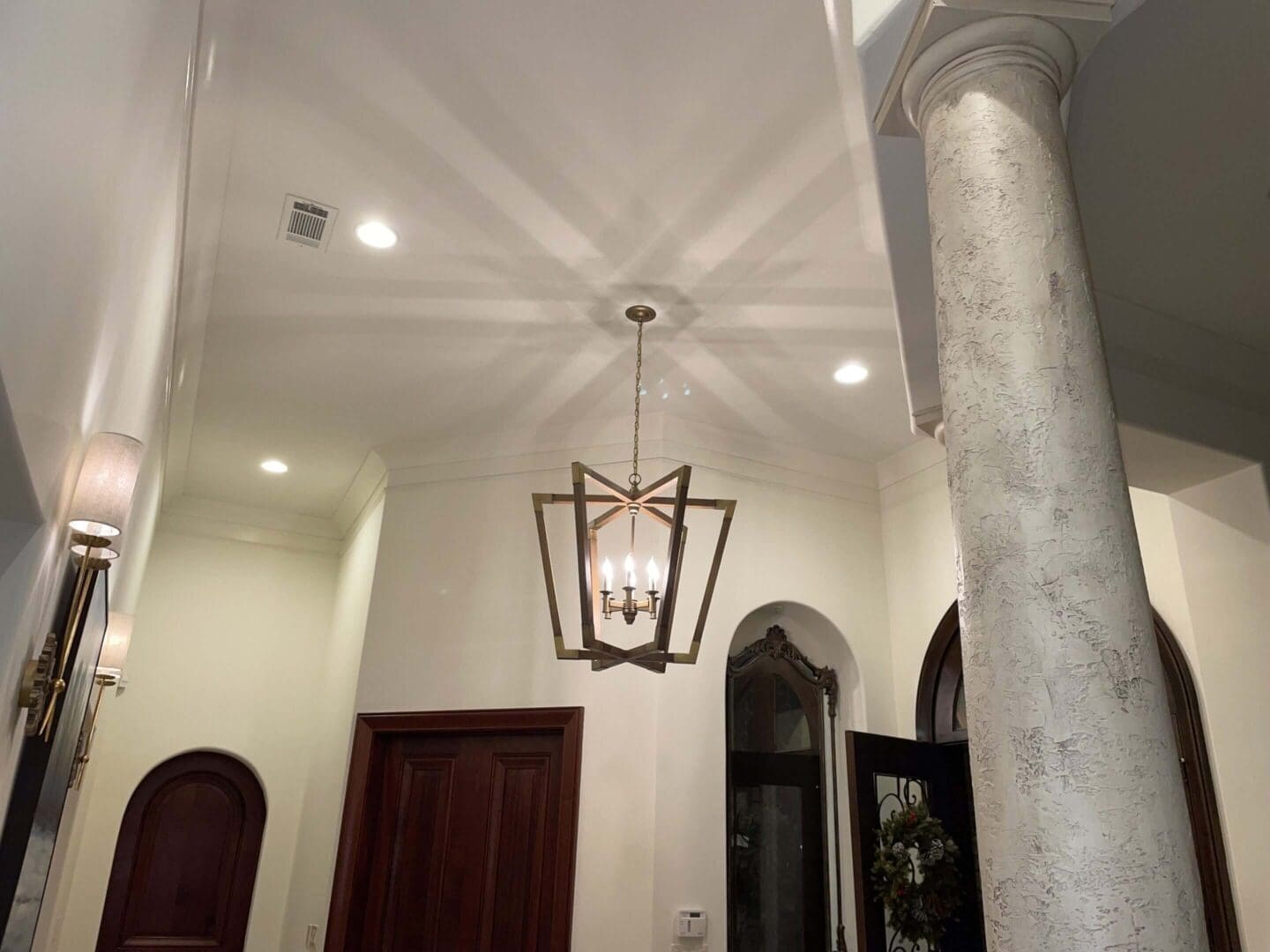 Elegant hallway with chandelier and column.